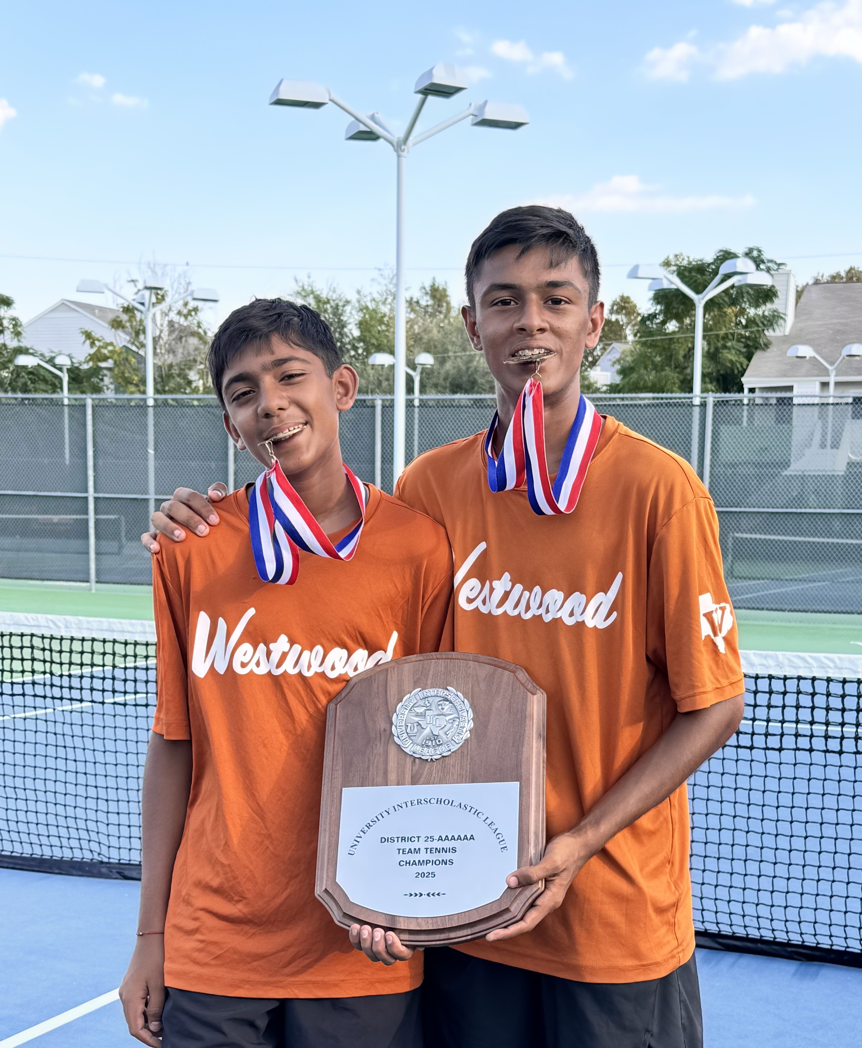 Aayush and his brother holding the 2025 District 25-AAAAAA Team Tennis Champions plaque